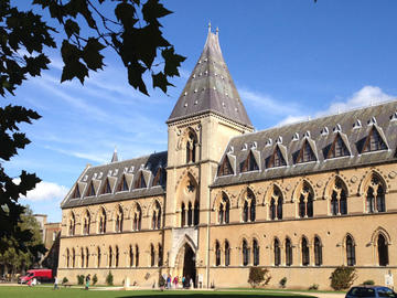 Image of museum of natural history, tall slate coloured roof against a bright blue sky