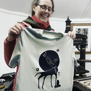 A woman holds up a t-shirt printed at a workshop